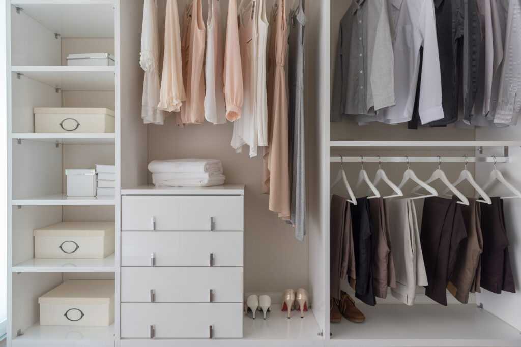 modern closet with clothes hanging on rail, white wooden wardrobe, interior design concept