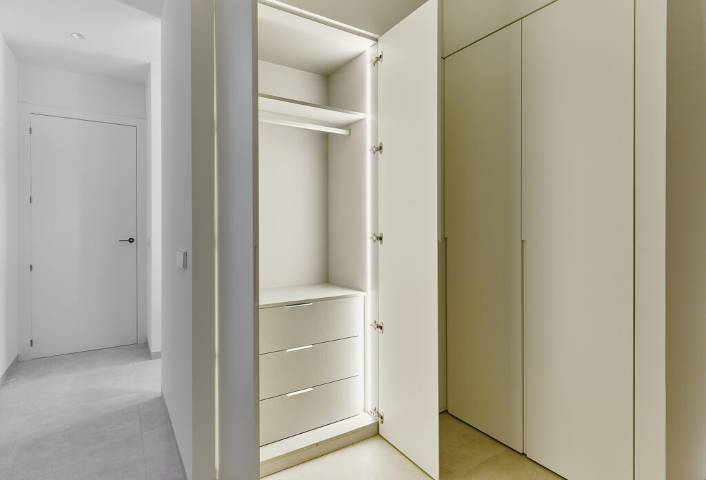 Opened door of light up white wooden fashionable built-in wardrobe, no people. Interior design ideas, comfort, luxury concept"r